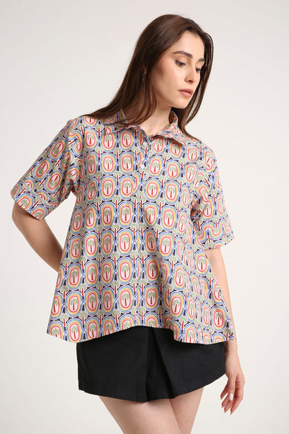 Woman wearing a patterned shirt and black shorts on a white background