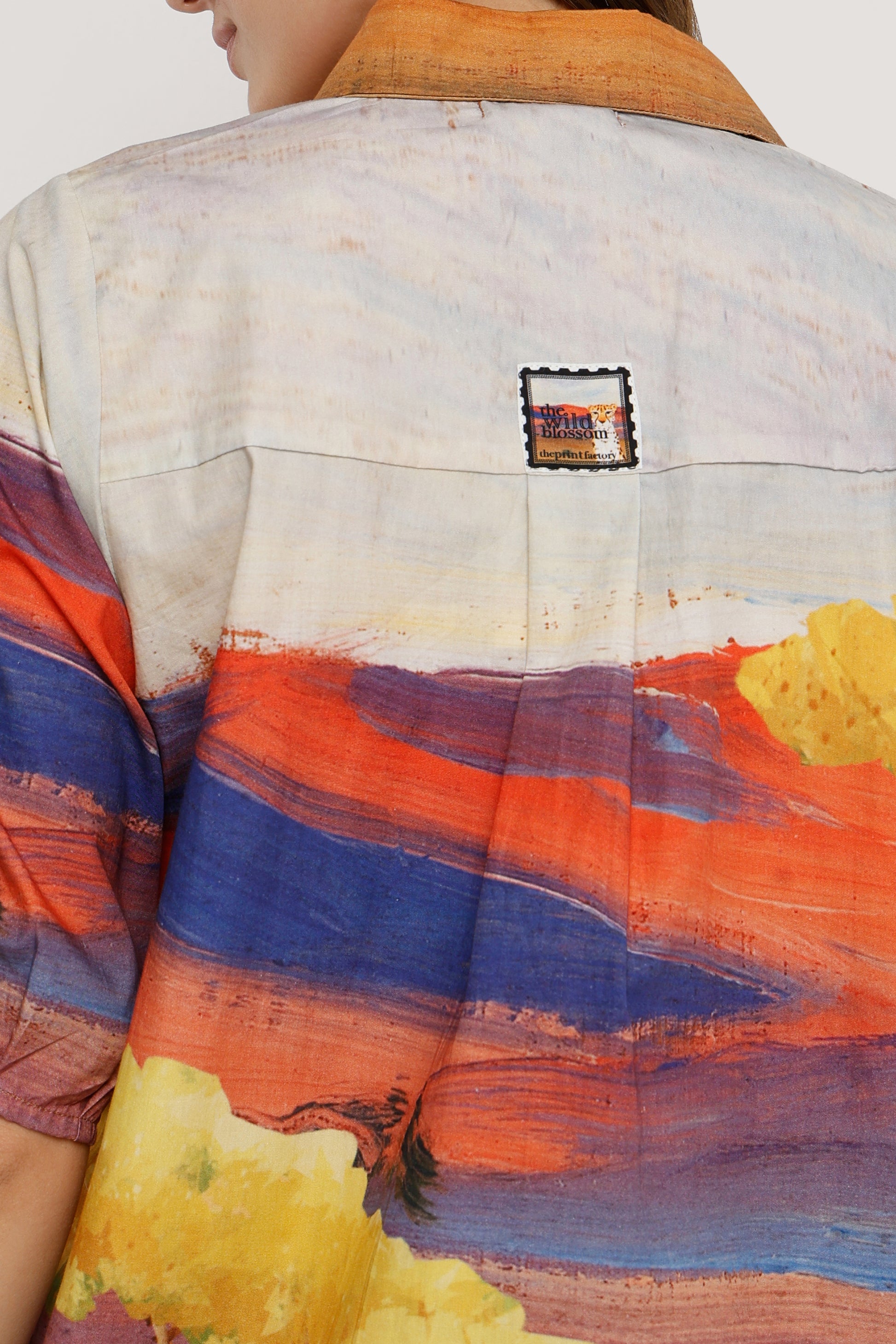 Person wearing a colorful shirt with abstract design and visible brand logo.