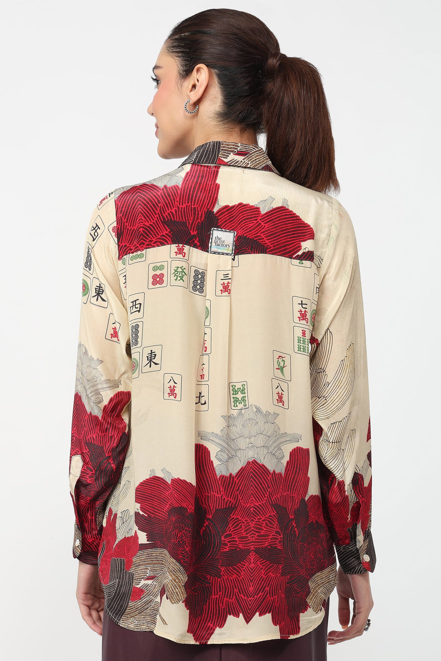 Woman wearing a shirt with a red and beige pattern on a white background