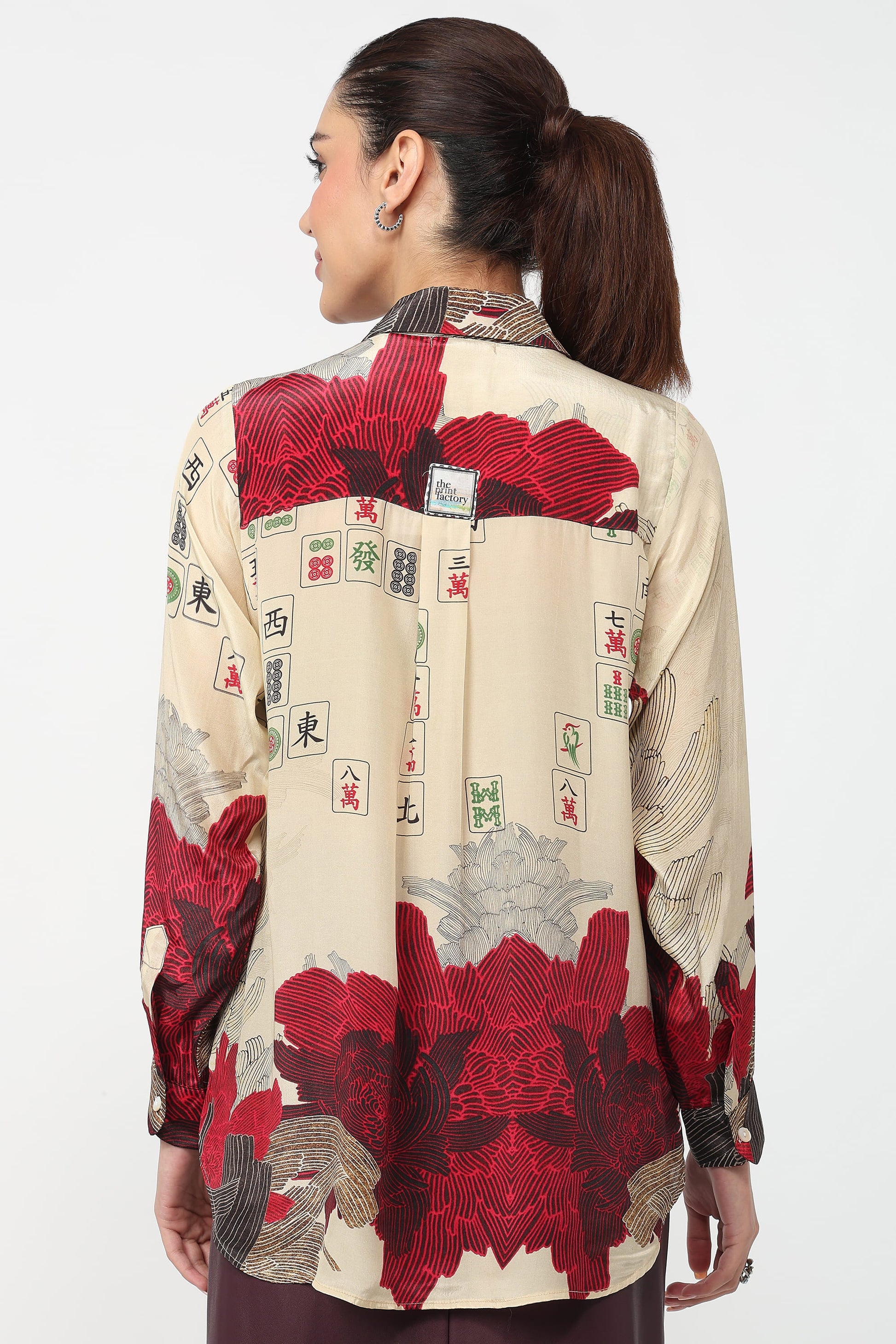 Woman wearing a shirt with a red and beige pattern on a white background