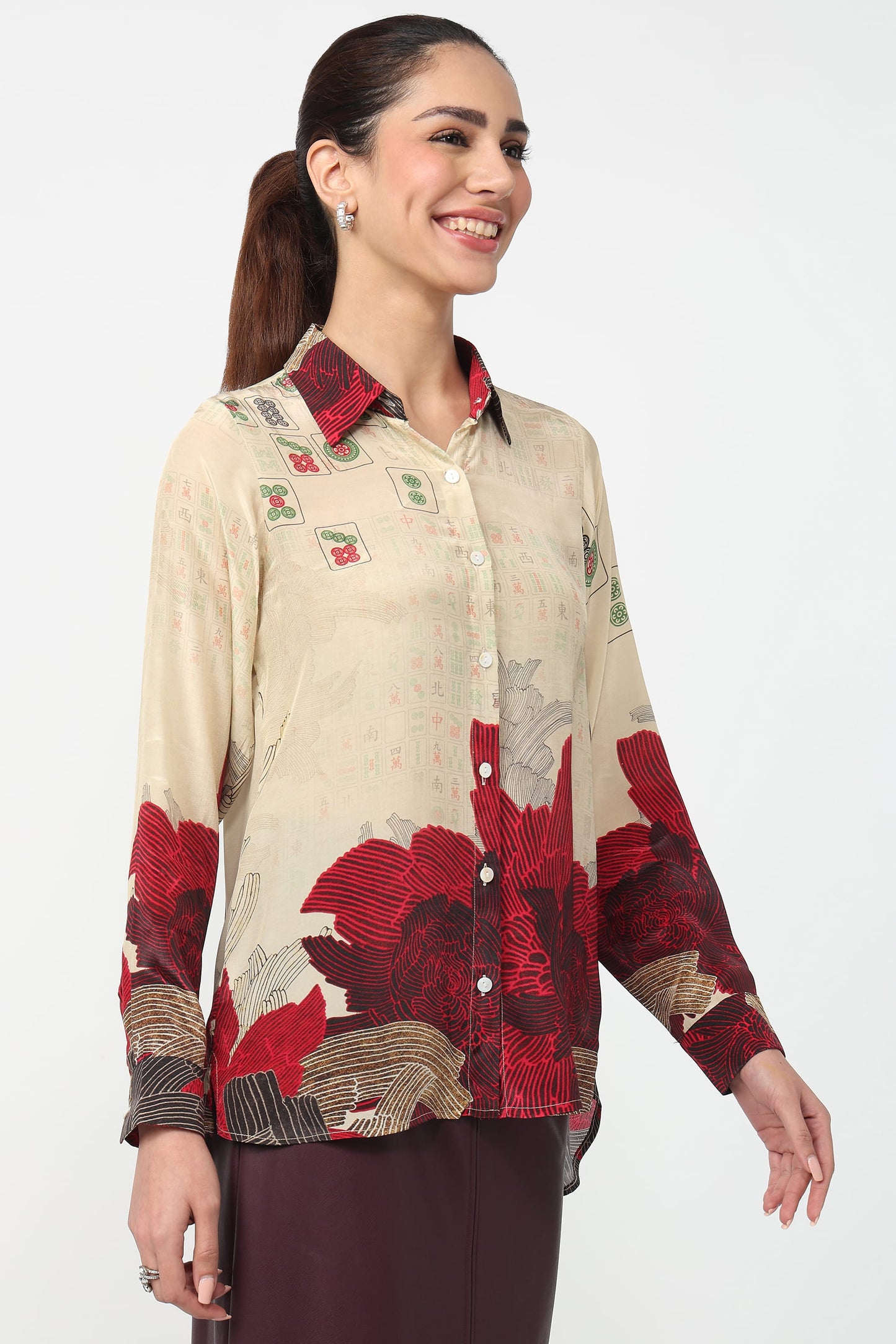 Woman wearing a patterned shirt with red and beige design on a white background