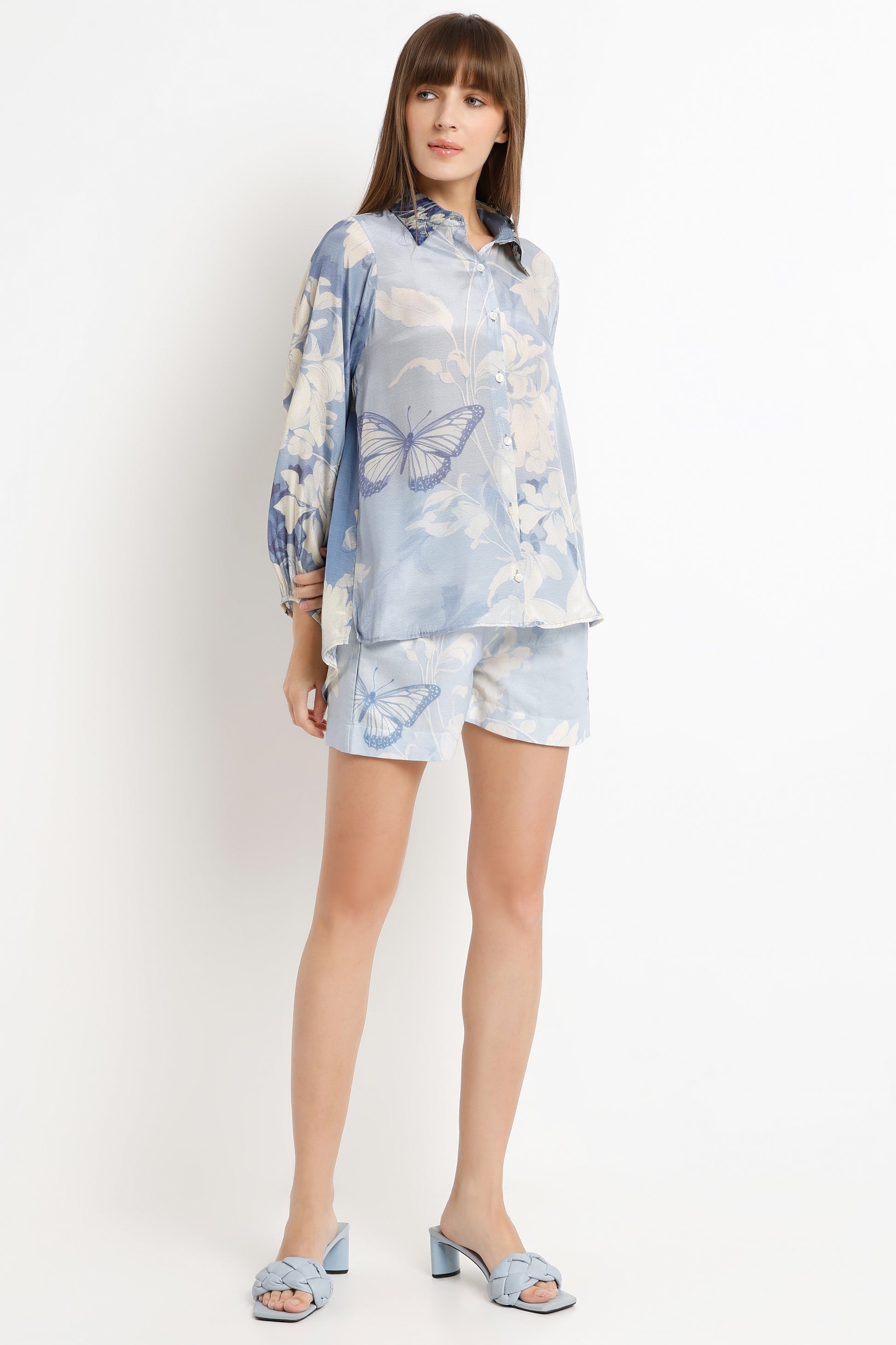 Woman wearing a light blue butterfly-patterned outfit on a white background
