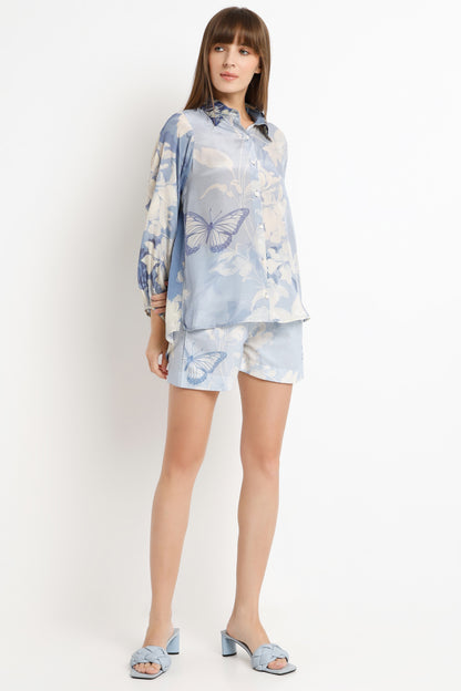 Woman wearing a light blue butterfly-patterned outfit on a white background