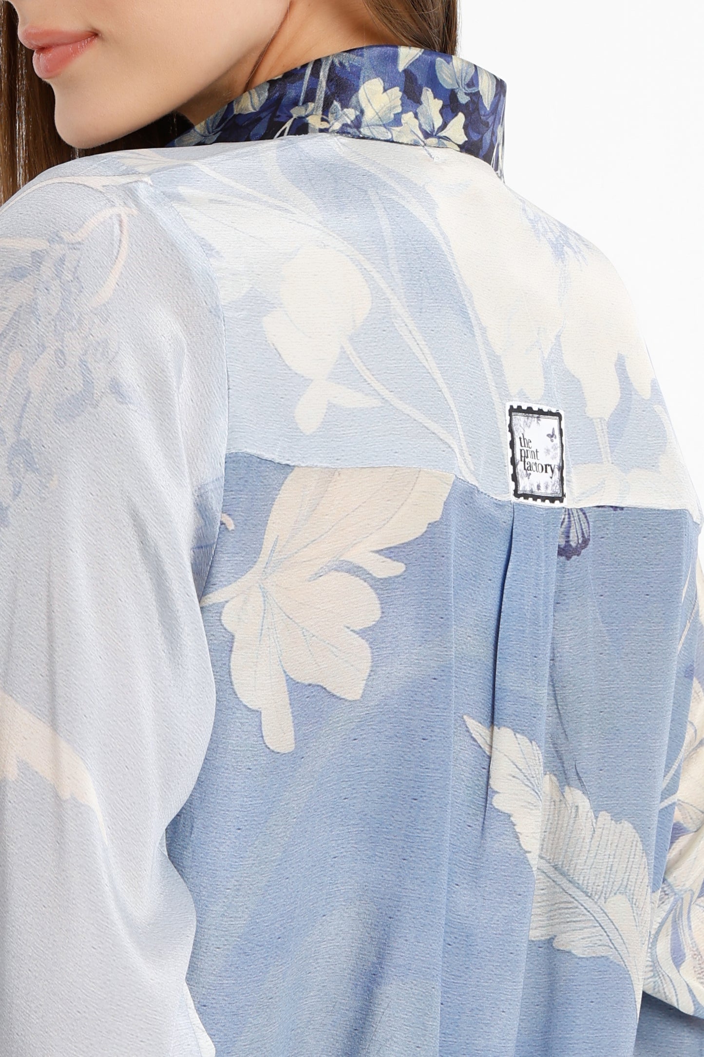 Close-up of a floral blouse with a brand label on a light background