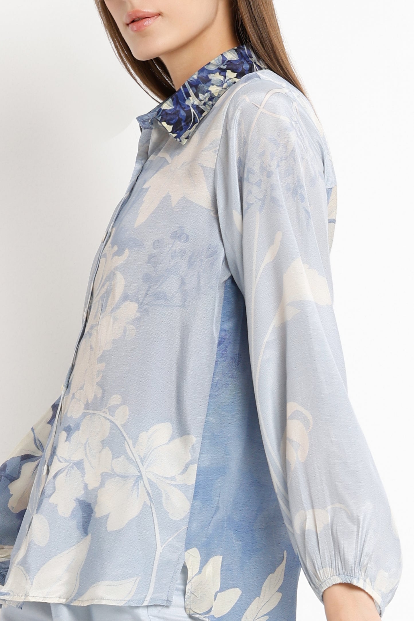 Light blue floral blouse worn by a person on a white background