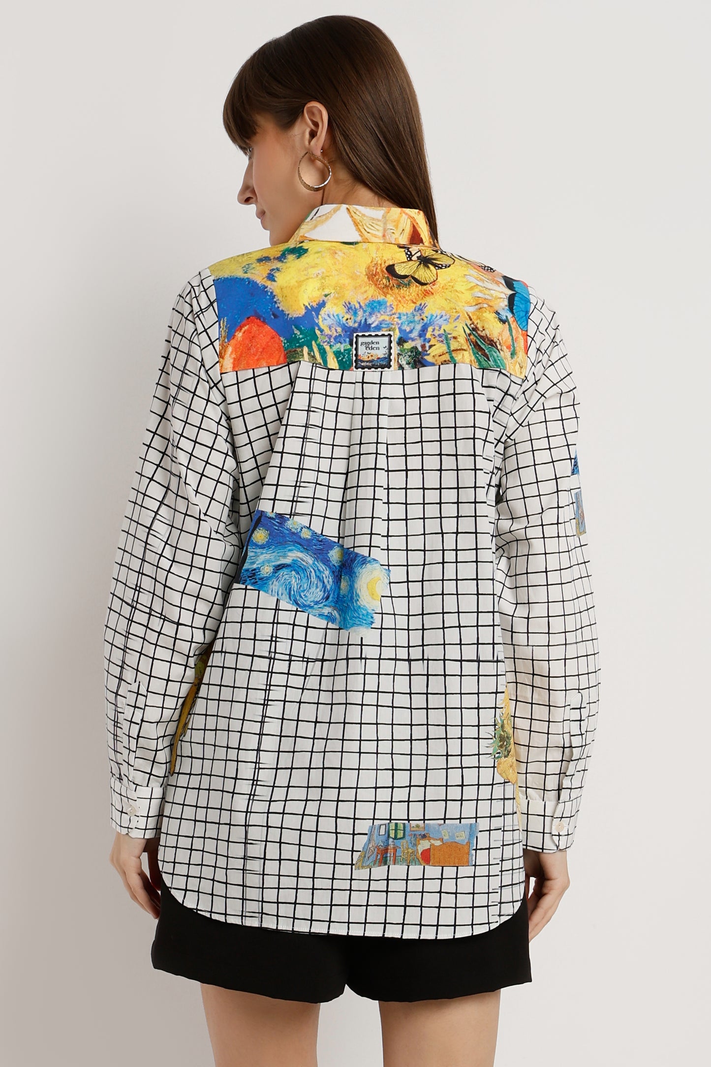 Woman wearing a checkered shirt with colorful floral and abstract designs on a plain background