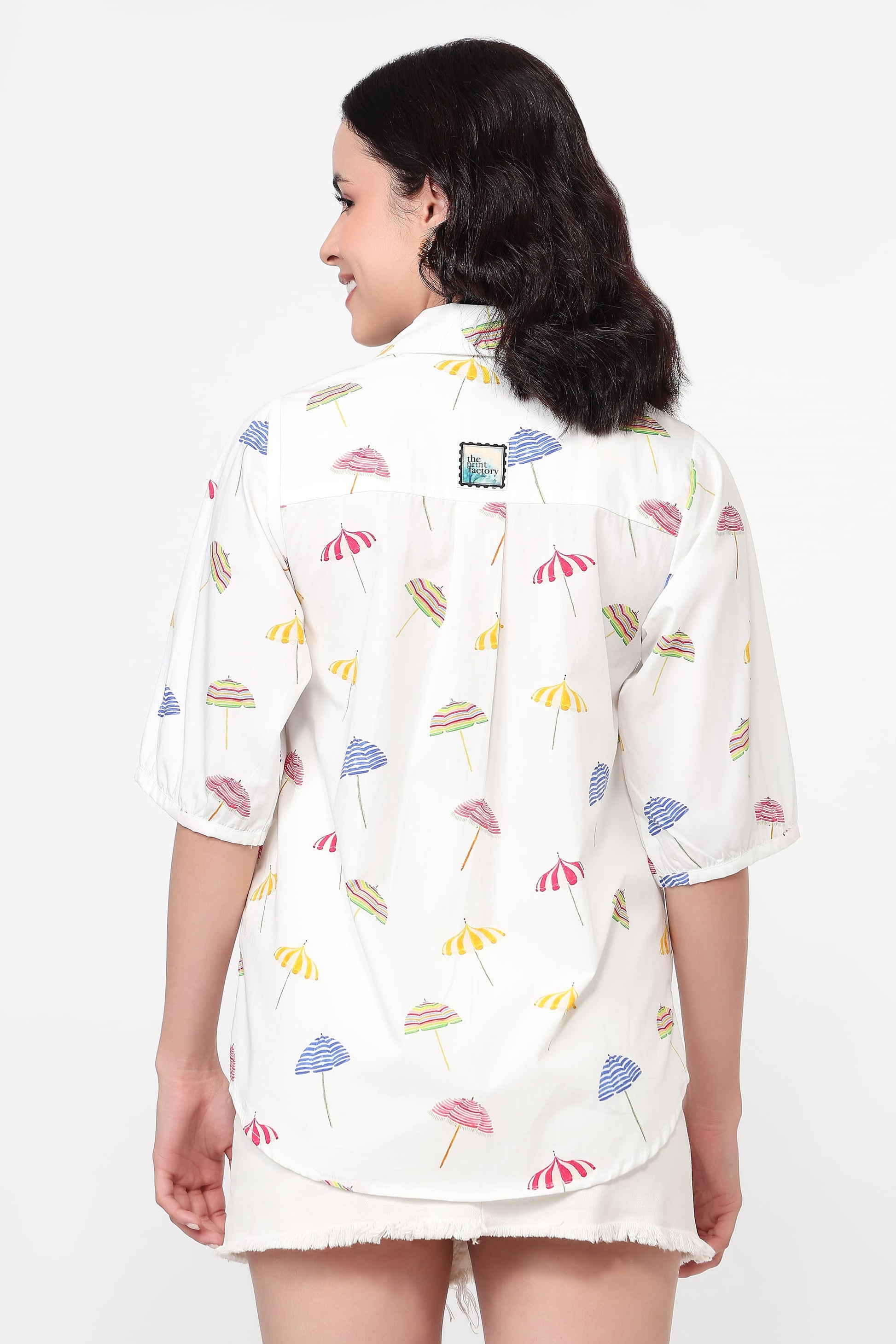 Woman wearing a white shirt with colorful floral pattern on a white background