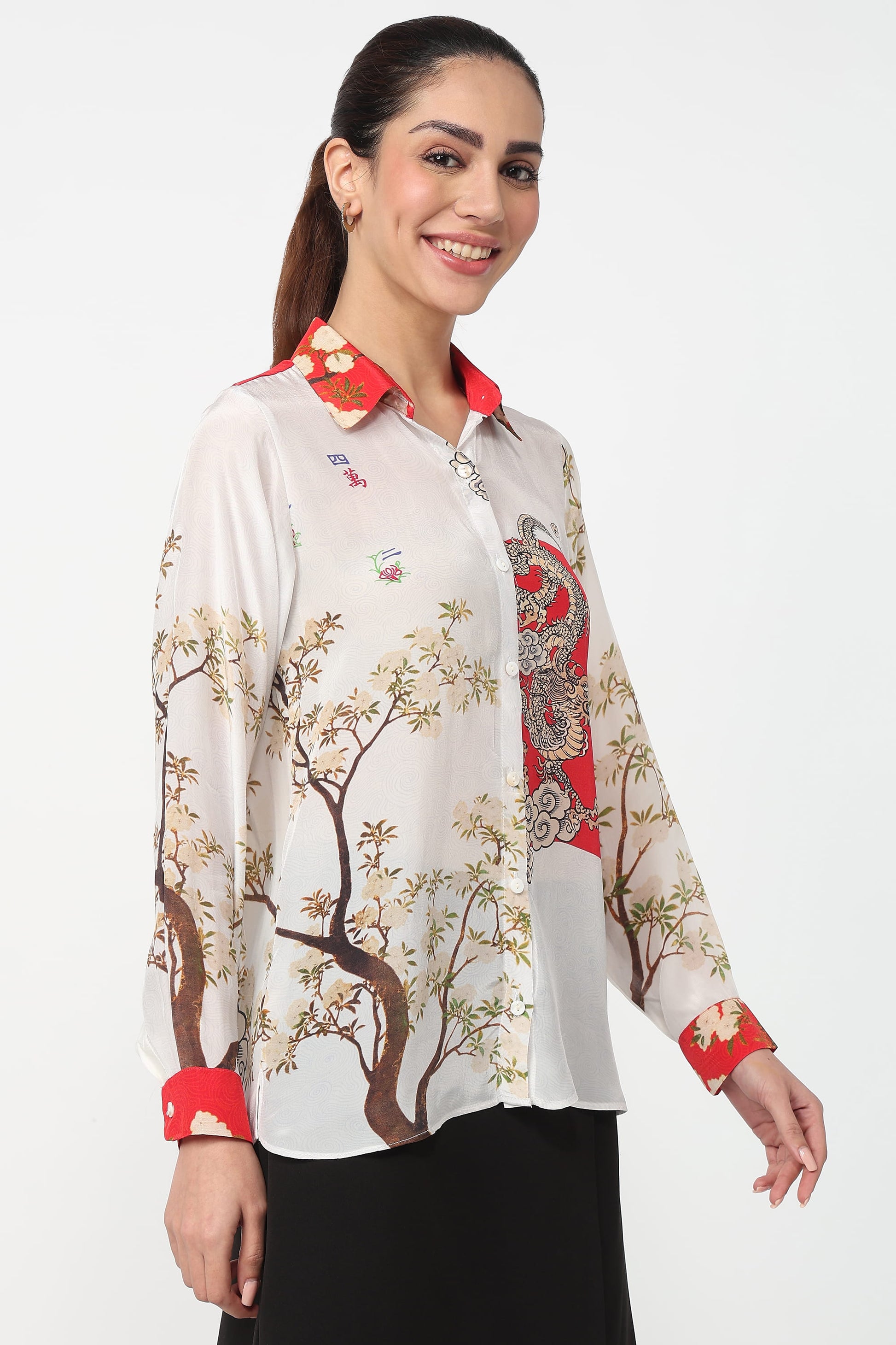 Woman wearing a patterned shirt with floral designs and red accents on a white background