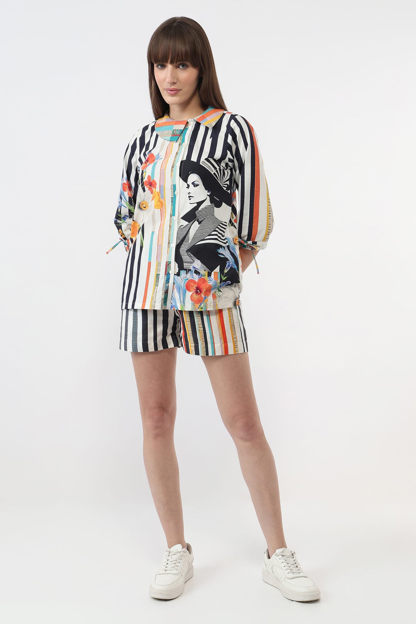A model wearing a matching two-piece set consisting of a long-sleeve top and shorts. The set features a black and white vertical stripe base with a colorful graphic print of a woman's portrait and floral accents.